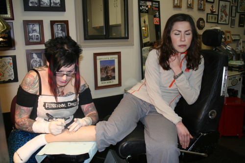 Marcii at Lady Luck Tattoo takes a Sharpie to Evonne's leg.