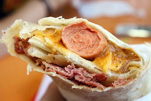 Oki Dog Two hot dogs covered with chili, cheese, and pastrami wrapped in a tortilla. (via flickr)
